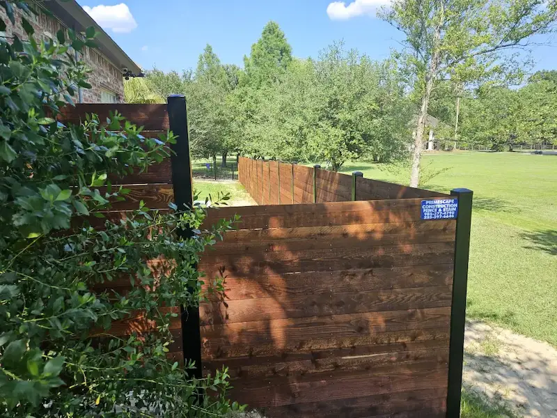smaller lightly stained wooden fence in livingston louisiana that meets up with metal fence